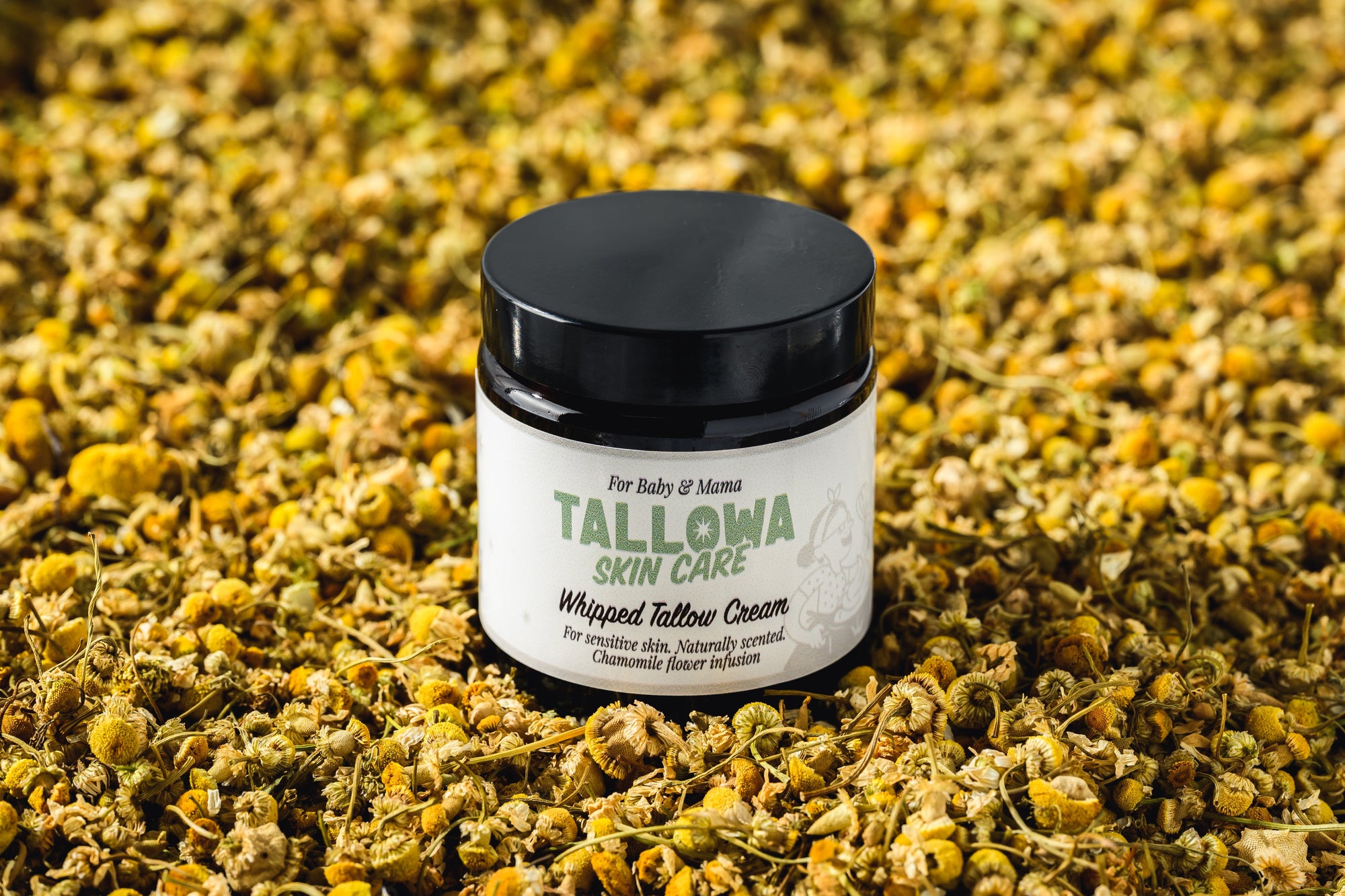 Tallowa Baby and Mama chamomile infused tallow balm surrounded by chamomile flowers for sensitive skin care